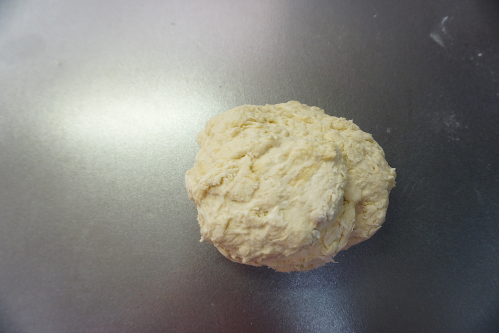 生地の状態を見ながら水を足し、さらに混ぜます。 ある程度生地がまとまったところで捏ね台に出し、塩を混ぜます。