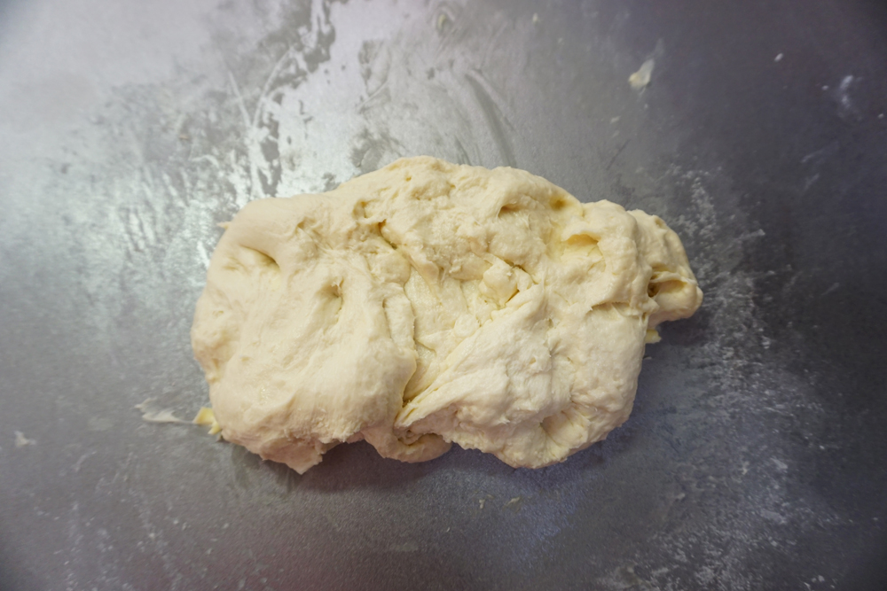 バターを加えてさらに捏ねます。 せっかくまとまった生地がバラバラになりますが、表面のテカリが消え、しっとりするまで約5分程度捏ねます。