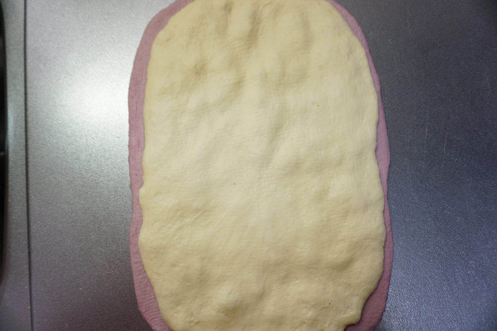 むらさき芋の生地にプレーンの生地をのせます。小豆の甘納豆がつぶれない程度に、綿棒で空気を抜きます。