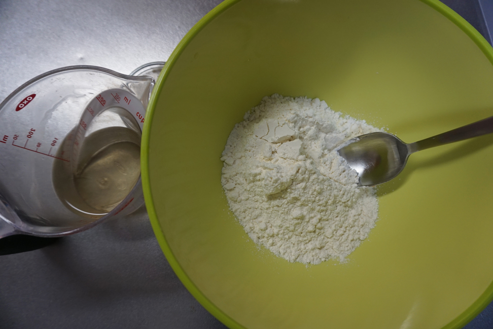 ボウルに溶いたドライイーストと、はちみつ入りの水を9割入れ、スプーンや菜箸で混ぜます。