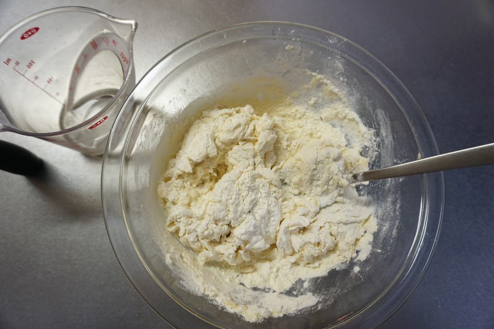 ドライイーストめがけて水を9割入れ、スプーンや菜箸で混ぜます。