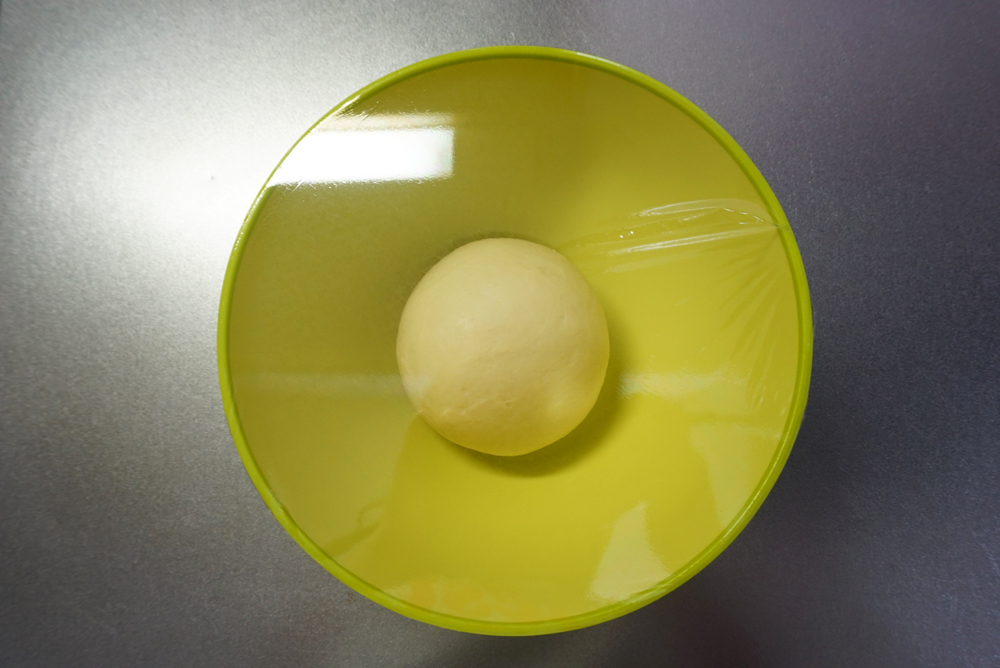 一次発酵：ラップをかけて、暖かい場所で約1時間発酵させます。夏場は常温、冬場はオーブンの発酵機能（35℃）を使うと便利です。時間はあくまでも目安です。生地が2倍になるまで待ってください。