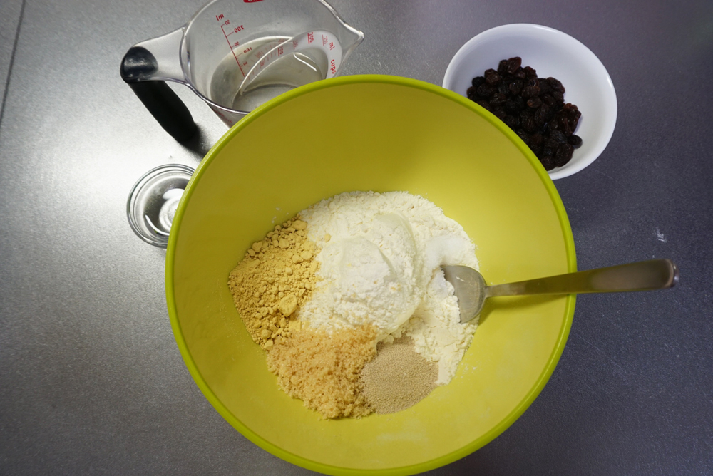 ボウルに強力粉、かぼちゃパウダー、ドライイースト、砂糖、塩を入れておきます。 ぬるま湯、レーズン、ココナッツオイルは別に用意しておきます。