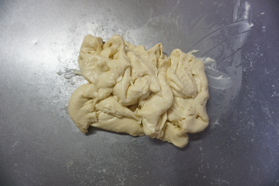 バターを入れてさらに捏ねます。 せっかくまとまった生地がバラバラになりますが、表面のテカリが消え、しっとりするまで約5分程度捏ねます。