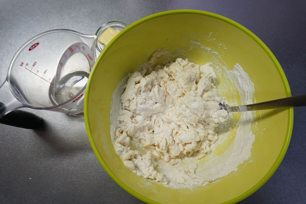 ドライイーストめがけて水を9割入れ、スプーンや菜箸で混ぜます。