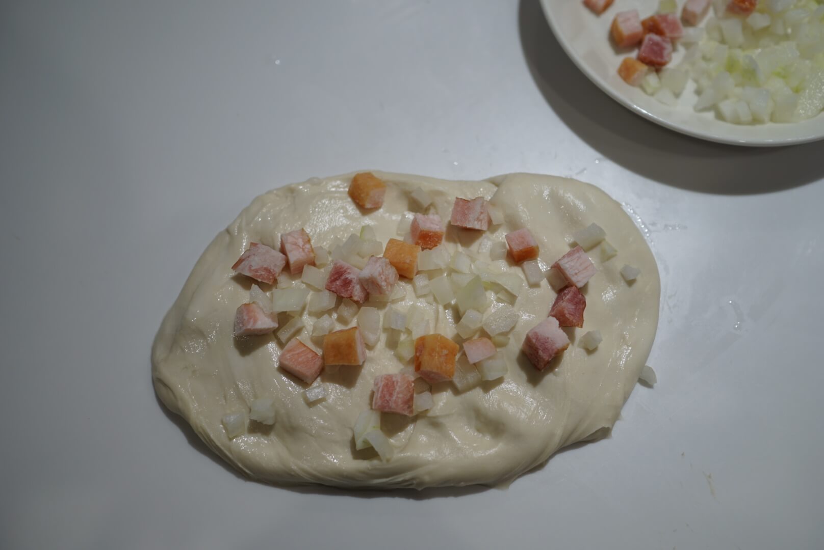 生地を長方形に広げ、玉ねぎとベーコンを1/4程度のせます。