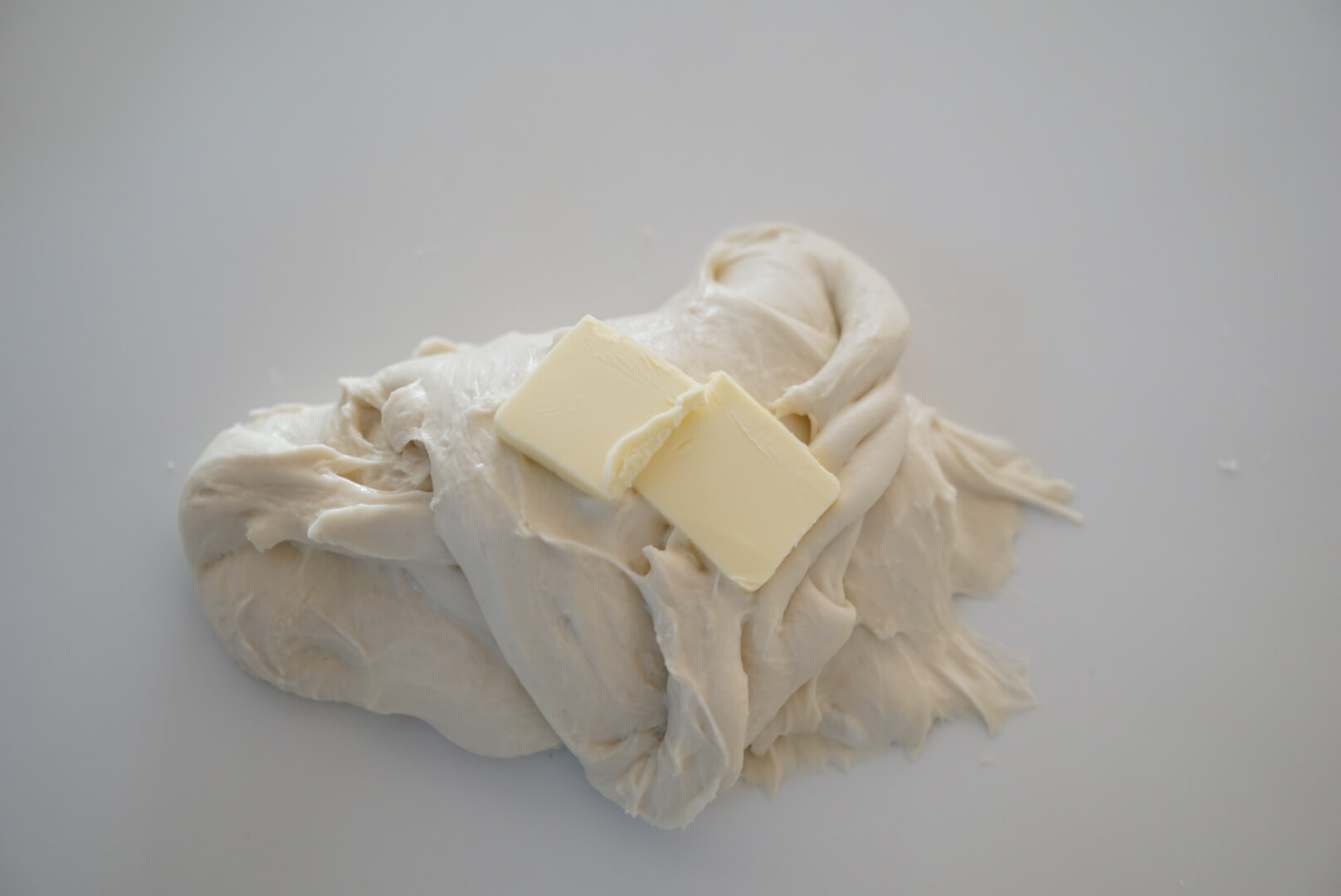 バターを加えてさらに捏ねます。 せっかくまとまった生地がバラバラになりますが、表面のテカリが消え、しっとりするまで約5分程度捏ねます。