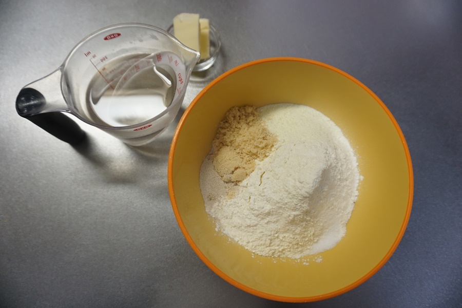 【生地作り】ボウルに強力粉・ドライイースト・砂糖・塩を入れておきます。ドライイーストと砂糖は隣り合わせにし、塩は離しておきます。バター、ぬるま湯、はそれぞれ別に用意しておきます。