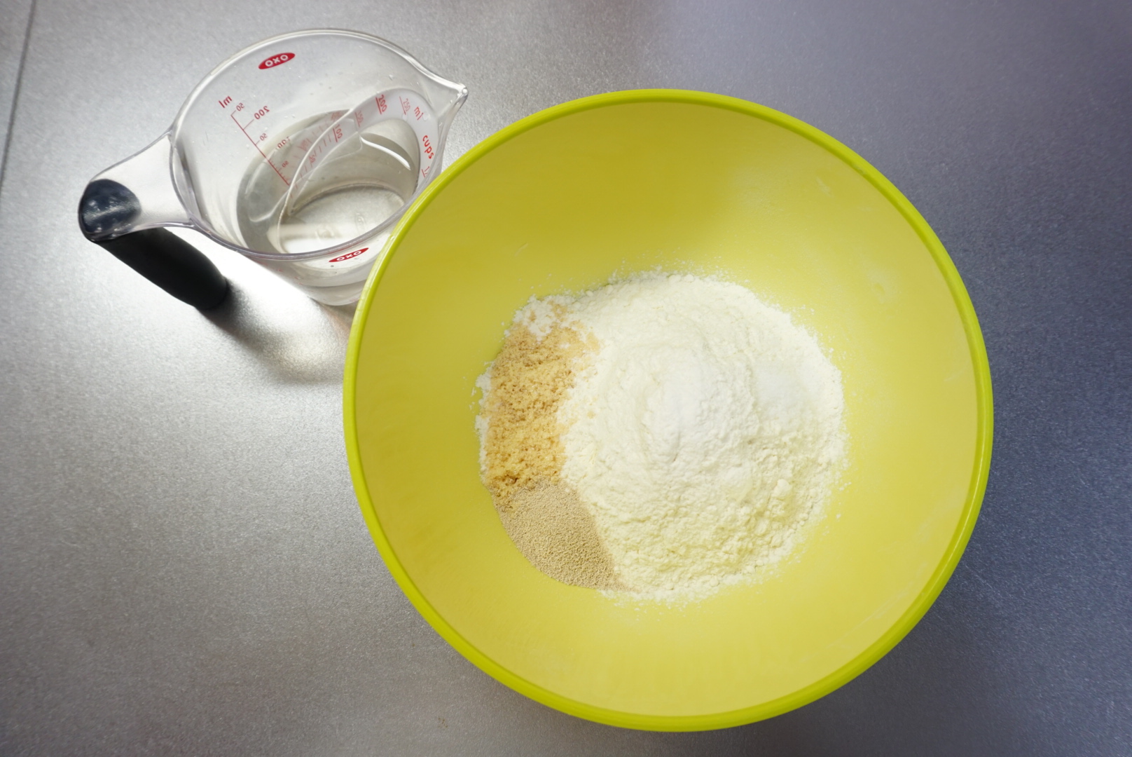 ボウルに準強力粉・ドライイースト・砂糖・塩を入れておきます。 ぬるま湯、ウィンナーはそれぞれ別に用意しておきます。