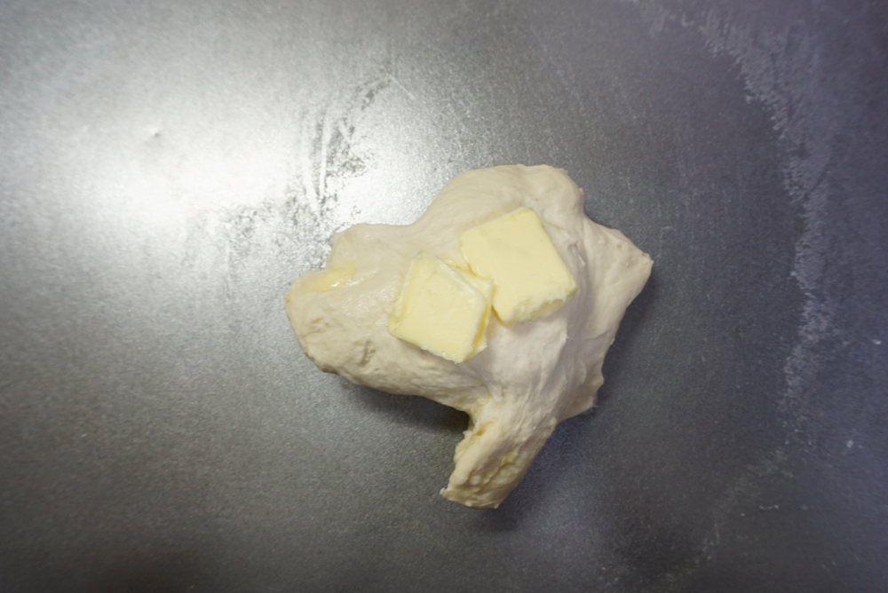 バターを入れてさらに捏ねます。 せっかくまとまった生地がバラバラになりますが、表面のテカリが消え、しっとりするまで約5分程度捏ねます。