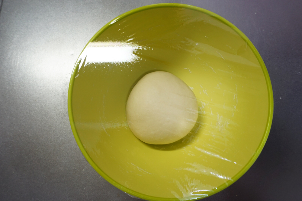 一次発酵:ラップをかけて、暖かい場所で約1時間発酵させます。夏場は常温、冬場はオーブンの発酵機能(35℃)を使うと便利です。時間はあくまでも目安です。生地が2倍になるまで待ってください。