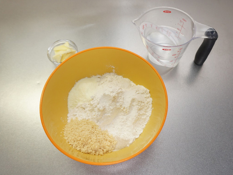 ボウルに強力粉を入れます。 ドライイーストと砂糖は隣り合わせで、塩は離してボウルに入れます。バター、ぬるま湯はそれぞれ別に用意しておきます。