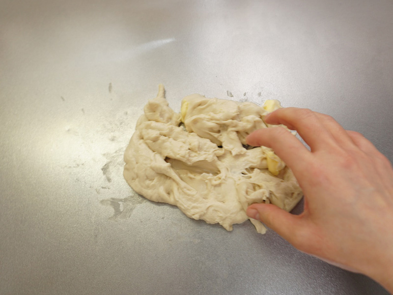 バターを入れてさらに捏ねます。 せっかくまとまった生地がバラバラになりますが、表面のテカリが消え、しっとりするまで約5分程度捏ねます。